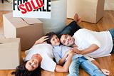 Parents and son moving house lying on floor