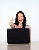 Happy woman with thumbs up using her laptop