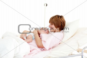 Smiling patient with newborn baby in bed