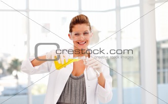 Attractive scientist examining a test-tube smiling at the camera