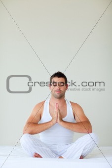 Young man doing yoga in bed with clossed eyes