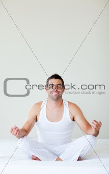 Smiling young man doing yoga in bed