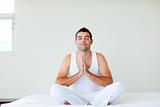 Man sitting on bed meditating with clossed eyes