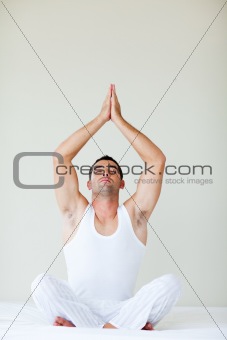 Young man doing meditation in bed