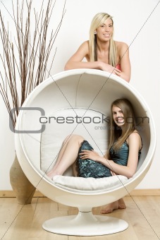 female relaxing in retro egg chair with friend