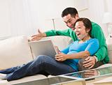 Couple Laughing While Looking at a Laptop Together