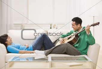 Asian couple on couch relaxing together.