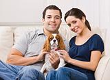 Couple with dog on their lap in their living room.