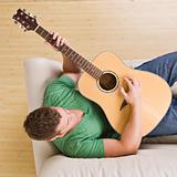 Man playing guitar on his couch.
