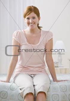 Attractive Redhead Woman Smiling and Sitting on her Bed