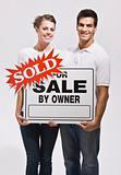 Couple Holding For Sale By Owners Sign
