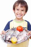 Smiling kid with three fresh fishes on table