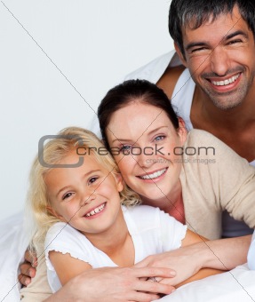 Parents and daughter on bed smiling at the camera