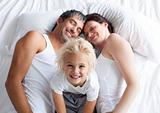 Little girl on bed with her parents smiling at the camera