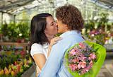 couple kissing in flower nursery