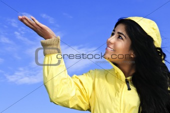 Beautiful young woman in raincoat checking for rain