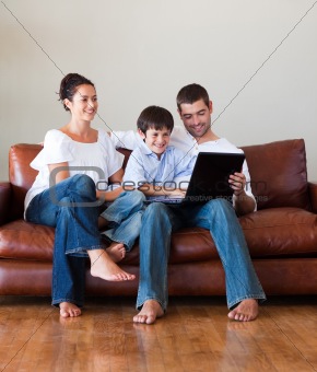 Parents and kid playing with a laptop on a couch