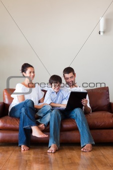 Parents and son playing with a laptop with copy-space