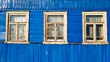 Three windows in the old blue wooden wall