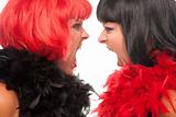 Red and Black Haired Women with Boas Screaming at Each Other on a White Background.