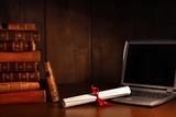 Antique books, diploma with laptop on desk