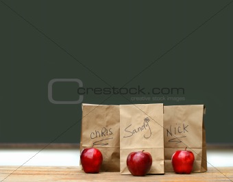 Lunch bags on desk with red apples