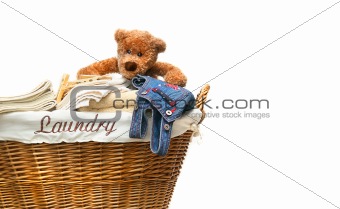 Laundry basket full of towels with teddy bear on white