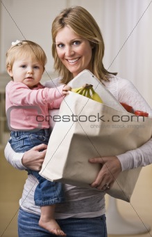 Mother Holding Daughter and Groceries