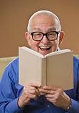Laughing senior male reading a book