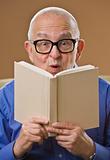 Silly senior man reading book.