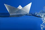 Paper boat floating over blue real water
