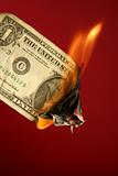 Dollar note burning in fire over red