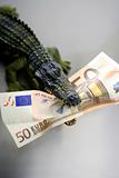 Toy cocodrile, aligator, with fifty euro banknote in his jaws