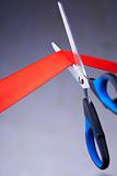 Closeup image of scissors cutting a red ribbon