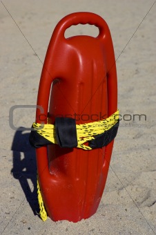Red plastic buoyancy aid in the sand