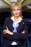 Blond air hostess (stewardess) in the empty ariliner cabin