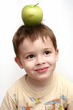 The cheerful child with a green apple on a head