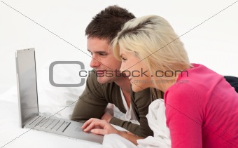 Portrait of a couple using a latop in bed