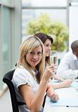 Smiling businesswoman drinking champagne in office