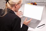Woman Sitting In Kitchen Using Laptop with Blank Screen. Screen can be easily used for your own message or picture using the included clipping path.