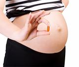belly of pregnant woman with capsules in hand