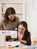 Mother Watching Daughter Use Sewing Machine