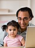 Smiling Father With Daughter Sitting By Laptop