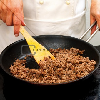 Chef frying minced meat in a pan