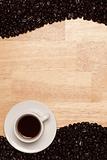 Dark Roasted Coffee Beans and Cup with Saucer on a Wood Textured Background.