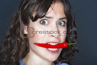 young brunette woman holding chili in her mouth