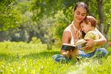 Happy mother and son reading a book outdoors