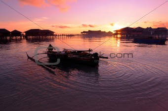 Fisherman prepares his traditional boat during sunset