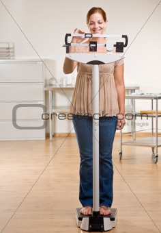 Woman weighing herself in doctorÕs office