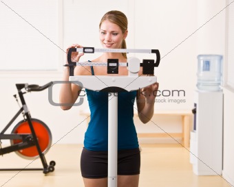 Woman weighing herself on scales in health club